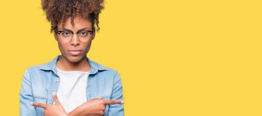 Güzel genç Afro-Amerikan kadın gözlük izole üzerinde işaretleme için her iki parmak, farklı yönde ile katılmıyorum arka plan