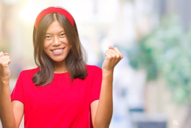 Genç Asyalı kadın kutluyor izole arka plan üzerinde şaşırttı ve başarı için kaldırdı kollarını açarak hayret ve gözleri açık. Kazanan kavramı.