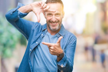 Orta yaş elle yapma çerçeve ve parmakları ile mutlu yüz gülümseyen izole arka plan üzerinde ağarmış komuta sizde. Yaratıcılık ve Fotoğrafçılık kavramı.