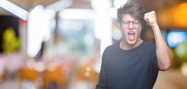 Üzerinde gözlük takan genç yakışıklı adam arka plan kızgın izole ve kızgın yetiştirme hayal kırıklığı ve öfke ile bağırarak süre öfkeli yumruk. Öfke ve agresif kavramı.