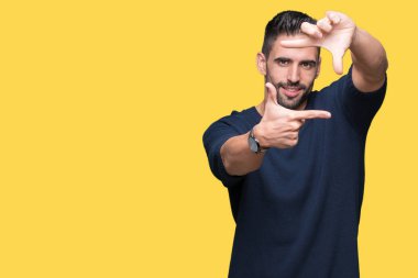 Elle yapma çerçeve ve parmakları ile mutlu yüz gülümseyen izole arka plan üzerinde kazak giyen genç yakışıklı adam. Yaratıcılık ve Fotoğrafçılık kavramı.