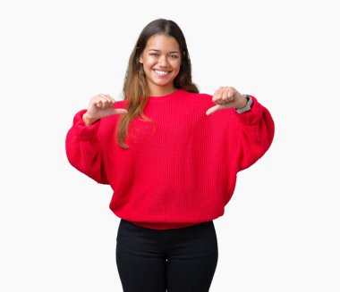 Yüzünde gülümseme ile kendinden emin görünüyorsun, kendini gururlu ve mutlu parmakları ile işaret izole arka plan üzerinde kırmızı kış kazak giyen genç güzel esmer kadın.