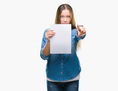 Genç kafkas kadın holding boş kağıt sayfası kamera ve size parmak ile işaret izole arka plan üzerinde el işareti, pozitif ve kendinden emin bir jest ön