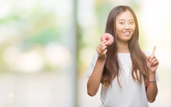 Joven Asiático Mujer Comer Donut Sobre Aislado Fondo Sorprendido Con — Foto de Stock