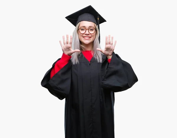 孤立した背景表示と指で上向きに大学院の制服を着て若いブロンドの女性数は自信を持って 幸せな笑みを浮かべている間 — ストック写真