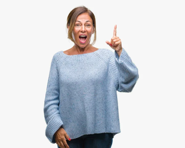 Başarılı fikirle izole arka plan işaret parmağı üzerinde kış kazak giyen orta yaş üst düzey İspanyol kadın. Çıktıktan ve mutlu. Bir numara.