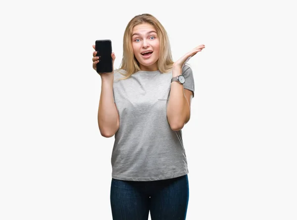 年轻的白人妇女显示屏幕的智能手机在孤立的背景非常高兴和兴奋 赢家表达庆祝胜利尖叫与大微笑和举手 — 图库照片