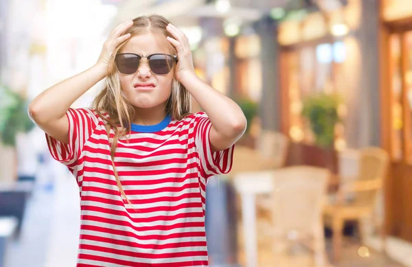 Young beautiful girl wearing sunglasses over isolated background suffering from headache desperate and stressed because pain and migraine. Hands on head.