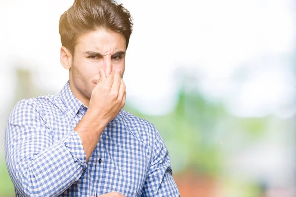 Genç yakışıklı iş adamı izole arka plan bir şey pis ve iğrenç kokulu, dayanılmaz koku, holding nefes burun parmaklar ile. Kötü kokuyor kavramı.