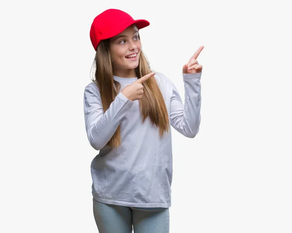 年轻美丽的女孩戴着红色的帽子孤立的背景微笑着 看着相机指向用两只手和手指的一侧 — 图库照片