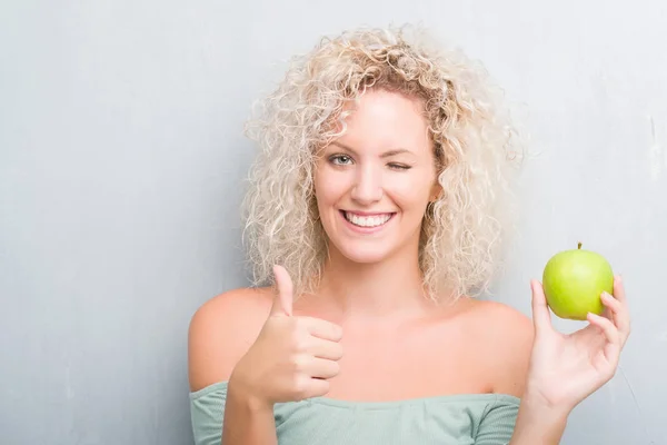 Giovane Donna Bionda Sfondo Grigio Grunge Mangiare Mela Verde Felice — Foto Stock