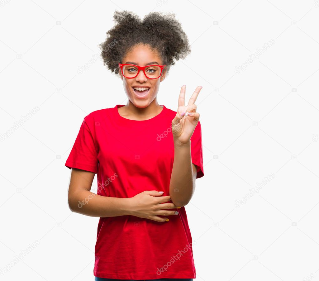 Young afro american woman wearing glasses over isolated background smiling with happy face winking at the camera doing victory sign. Number two.