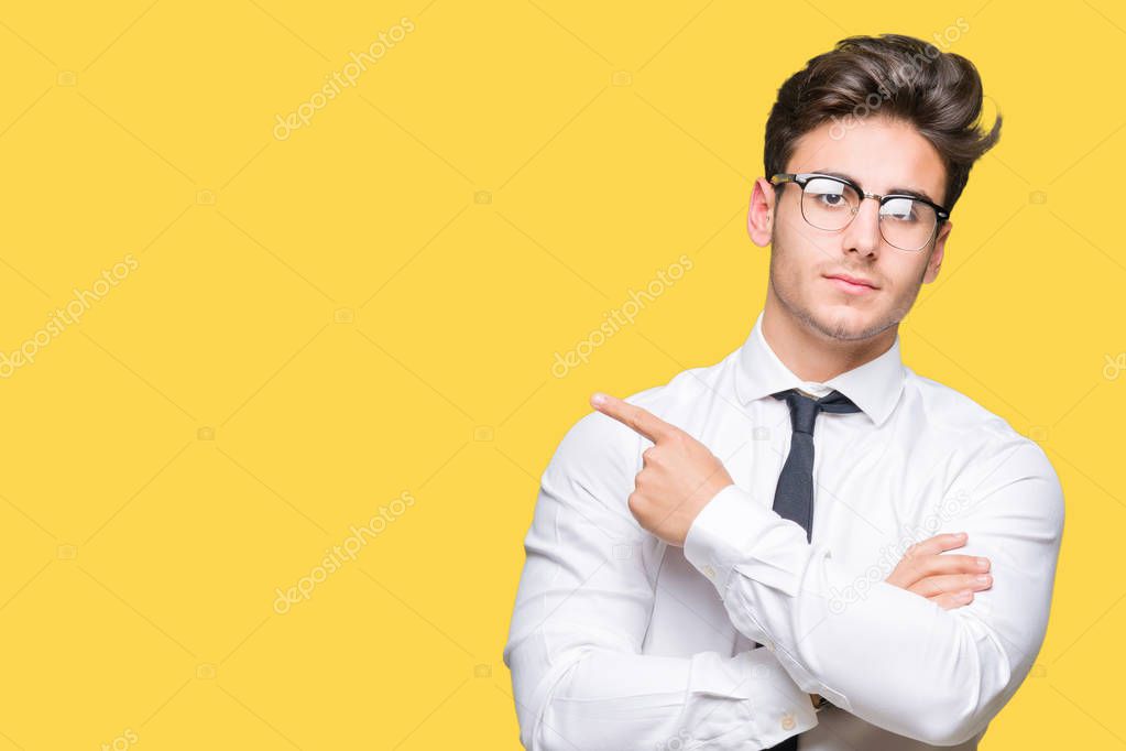 Young business man wearing glasses over isolated background Pointing with hand finger to the side showing advertisement, serious and calm face