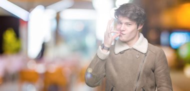 Üzerinde kış ceket giyen genç yakışıklı adam arka plan ağız izole ve parmak ile ZIP olarak Dudaklarını kapa. Gizli ve sessiz, tabu söz