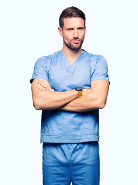 Yakışıklı Doktor izole arka plan şüpheci ve sinir, onaylamayan ifade yüz çapraz kolları üzerinde tıbbi üniforma giyen adam. Negatif kişi.