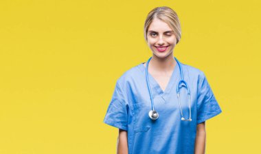 Genç güzel sarışın doktor cerrah hemşire kadın seksi bir ifadeyle, neşeli ve mutlu yüzünü kameraya bakarak göz kırpıyor izole arka plan üzerinde.