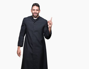 Genç Hıristiyan rahip yüzünde kocaman bir gülümseme ile izole arka plan üzerinde kameraya bakarak yan el ve parmak ile işaret.