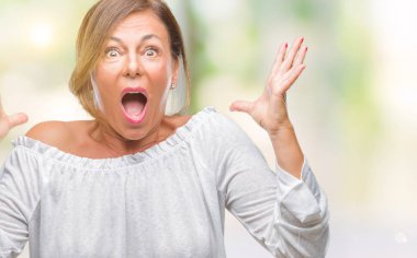 Orta yaş üst düzey İspanyol kadın deli kutluyor arka plan izole ve başarı için kaldırdı kollarını açarak hayrete ve heyecanlı çığlık gözleri açık. Kazanan kavramı