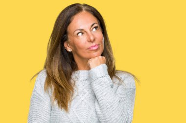 Üzerinde kış kazak giyen güzel orta yaş yetişkin kadın arka plan çene düşünme hakkında soru, dalgın ifade üzerine el ile izole. Düşünceli yüzüyle gülümsüyor. Şüphe kavramı.