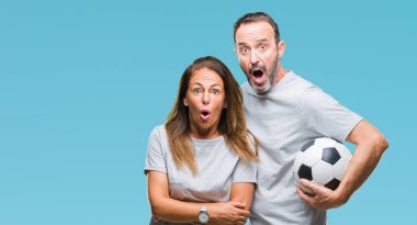 Orta yaş İspanyol çift futbol futbol topu izole arka plan üzerinde bir sürpriz yüz, korkuyor ve heyecanlı korku ifadesi ile şok korkmuş holding