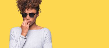 Tırnak ısırma dudaklarından eller güzel genç Afro-Amerikan kadın stresli ve gergin ile izole arka plan üzerinde güneş gözlüğü takıyor. Anksiyete sorunu.