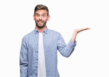 Neşeli sunulması ve kameraya bakarak avucunun ile işaret gülümseyen izole arka plan üzerinde beyaz t-shirt giyen genç yakışıklı adam.