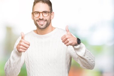 Yakışıklı delikanlı izole arka plan başarı işareti el ile pozitif jest yapıyor üzerinde gözlük takan başparmak gülümseyen ve mutlu. Neşeli bir ifadeyle, kazanan jest kameraya bakıyor.