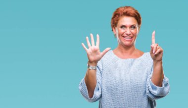 Gösterilen arka plan üzerinde kış kazak giyen Atrractive üst düzey beyaz Kızıl saçlı kadın izole ve parmakları ile işaret kendinden emin ve mutlu gülümseyerek süre 6 numara.