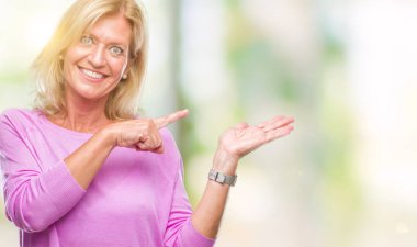 Orta yaş sarışın kadın üzerinden hayran ve el ile sunulması ve parmak ile işaret ederken kameraya gülümseyen izole arka plan.