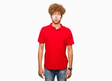 Kırmızı t-shirt şişirme yanakları komik surat ile giyen afro saçlı Genç yakışıklı adam. Ağız ile hava, deli ifade şişirilmiş.