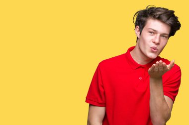 Bir öpücük el ile güzel ve seksi olmak hava üfleme kamera bakarak izole arka plan üzerinde kırmızı t-shirt giyen genç yakışıklı adam. Aşk ifade.