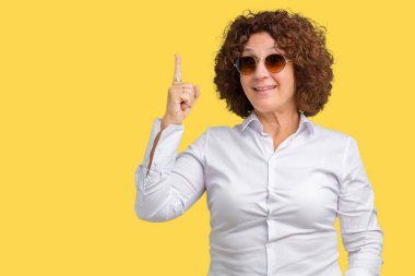 Güzel orta ager üst düzey iş kadını ile başarılı fikir izole arka plan işaret parmağı üzerinde güneş gözlüğü takıyor. Çıktıktan ve mutlu. Bir numara.