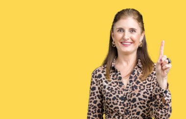 Gösterilen ve kendinden emin ve mutlu gülümseyen bir parmak ile işaret eden oktan yukarı arka plan üzerinde leopar elbise giyen güzel orta yaş olgun zengin kadın izole.