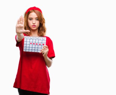 Genç güzel kadın adet takvim ile tutarak izole arka plan üzerine açık dur işareti ile ciddi ve kendine güvenen ifade, savunma hareketi yaparken el