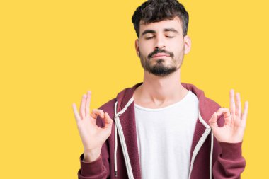 Yakışıklı delikanlı izole arka plan üzerinde dinlenmek ve gülümseyen gözlerle parmak ile meditasyon jest yapıyor kapalı. Yoga kavramı.