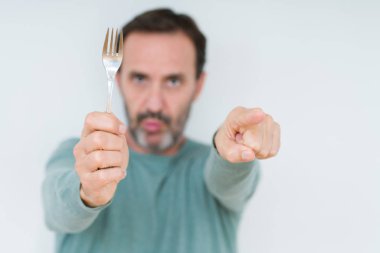 Komuta sizde holding gümüş çatal izole arka kamera ve size parmak ile işaret üzerine, el işareti, pozitif ve kendinden emin bir jest ön