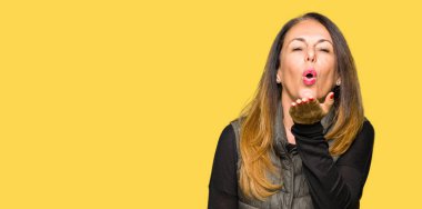 Bir öpücük el ile güzel ve seksi olmak hava üfleme kamera bakarak kış yelek giyen güzel orta yaş kadın. Aşk ifade.