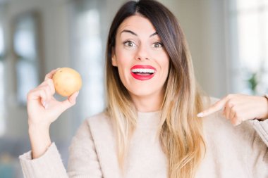 Kendisi için sürpriz yüz işaret parmağı taze patates evde tutan genç güzel kadın