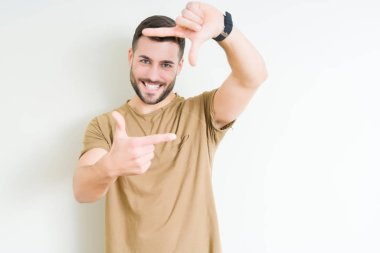 Yakışıklı delikanlı elle yapma çerçeve ve parmakları ile mutlu yüz gülümseyen izole arka plan üzerinde. Yaratıcılık ve Fotoğrafçılık kavramı.