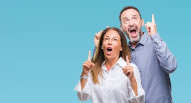 Orta yaş İspanyol iş çift izole arka plan üzerinde hayret ve yukarıya bakıp parmakları ile işaret şaşırttı ve silah kaldırdı.