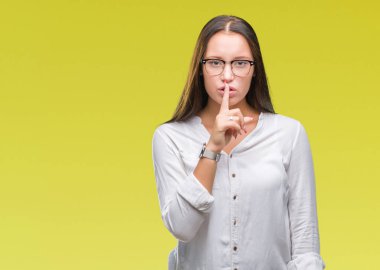 Dudaklarında parmak ile sessiz olmanı izole arka plan üzerinde gözlük takan Genç beyaz güzel iş kadını. Sessizlik ve gizli kavramı.