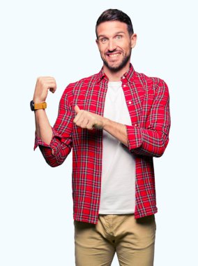 Yakışıklı adam rahat gömlek giymiş emin gülümseyen arkasından el ve kadar başparmak ile işaret