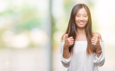 Genç Asyalı kadın el ile pozitif jest yapıyor izole arka plan başarı işareti üzerinde başparmak gülümseyen ve mutlu. Neşeli bir ifadeyle, kazanan jest kameraya bakıyor.