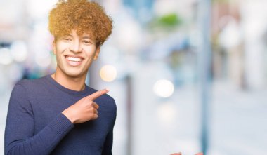 Gülümseyen ve iki ile işaret kamera bakarak afro saçlı yakışıklı delikanlı eller ve yan parmak.