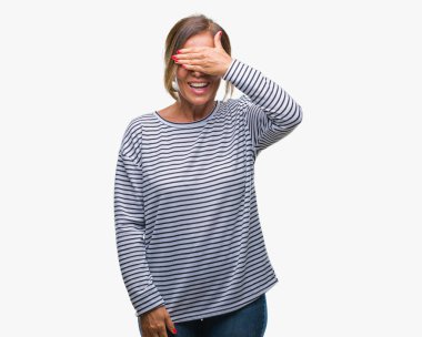 Orta yaş üst düzey İspanyol kadın gülümsüyor ve gözleri için sürpriz kapsayan yüz el ile gülüyor izole arka plan yüzünden. Kör kavramı.