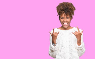 Deli ifade rock simge elle yapıyor ile bağırarak izole arka plan üzerinde kış kazak giyen güzel genç Afro-Amerikan kadın. Müzik yıldızı. Ağır kavramı.
