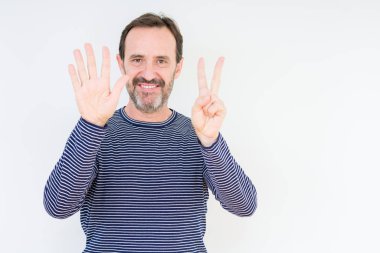 Üst düzey yakışıklı gösteren ve parmakları ile işaret izole arka plan üzerinde kendinden emin ve mutlu gülümseyerek süre yedi numara.