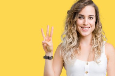 Genç güzel sarışın kadın gösterilen ve parmakları ile işaret izole arka plan yüzünden kendinden emin ve mutlu gülümseyerek iken üçüncü.
