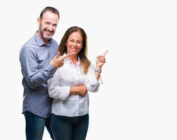 中年西班牙商业夫妇在孤立的背景与一个灿烂的笑容在脸上 用手和手指指着一边看着镜头 — 图库照片