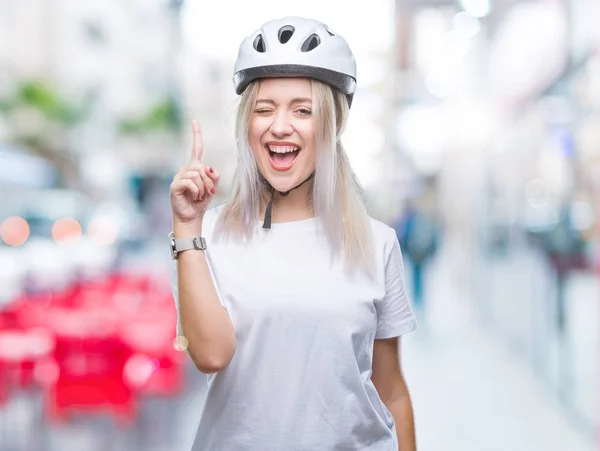 年轻的金发女郎穿着自行车安全头盔在孤立的背景下 指着成功的想法 退出和快乐 第一个 — 图库照片